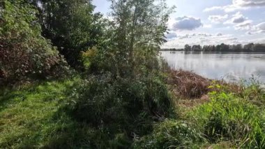 Bavyera sonbaharında ışık dalgaları ve bulutların yansıdığı göl.