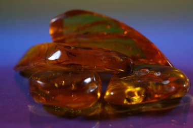 Amber gemstone on pink and blue background. Shallow depth of field                               