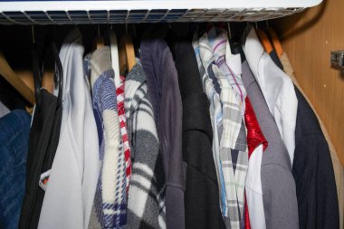 Dolap dolup taşıyor ve rengarenk bir şekilde ceketler, pantolonlar, kazaklar ve çantalarla karıştırılıyor.