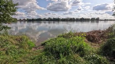 Bavyera sonbaharında ışık dalgaları ve bulutların yansıdığı göl.