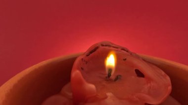Sarı alevli kırmızı mum yavaş çekimde kırmızı zemine karşı dumanla yanar ve söner.
