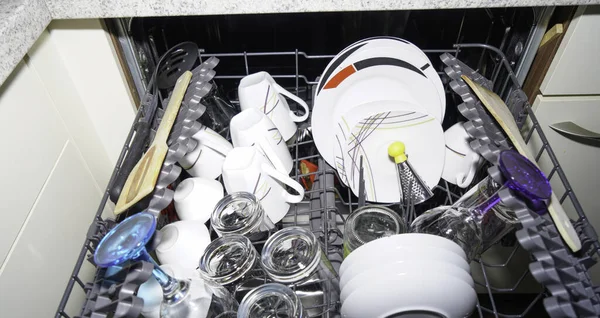 Dishwasher with freshly washed plates, glasses and cutlery, household goods