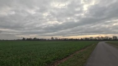 Araba ufukta geziniyor. Tarlalar, çayırlar ve bulutlar arasında.