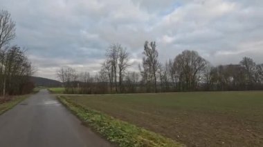 Bulutlu bir gökyüzünün altında taşra yolunda araba yolculuğu