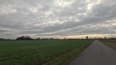 Bulutlu bir gökyüzünün altında taşra yolunda araba yolculuğu