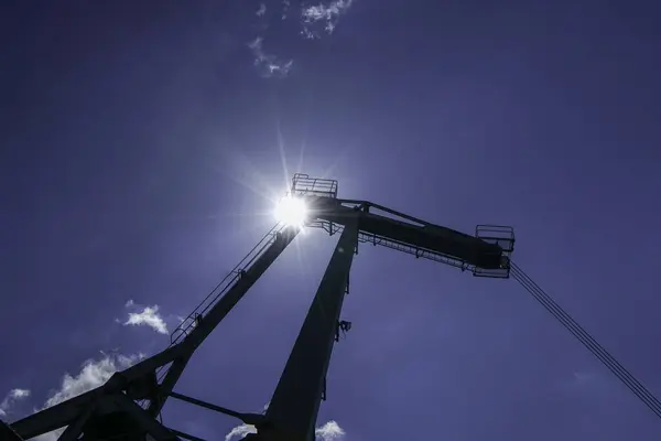Crane for industrial handling of goods in the port with blue sky in the back light