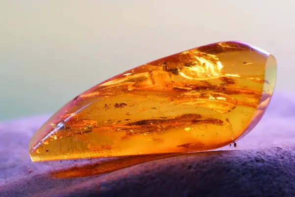Amber gemstone on pink and blue background. Shallow depth of field                               