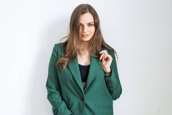 Красивая девушка в зеленой куртке в офисном стиле стоит на белом фоне
