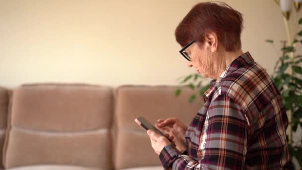 80歳の女性が電話で座り 自宅で仕事をしている 電話で手を閉じる — ストック動画