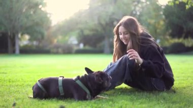 Genç bir kız köpeği ile parkta oynuyor. Çimlerin üzerinde 4K görüntüleri var.