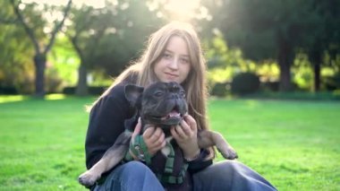 Genç bir kız köpeği ile parkta oynuyor. Çimlerin üzerinde 4K görüntüleri var.