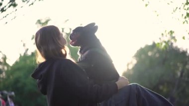 Genç bir kız köpeği ile parkta oynuyor. Çimlerin üzerinde 4K görüntüleri var.