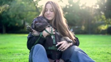 Genç bir kız köpeği ile parkta oynuyor. Çimlerin üzerinde 4K görüntüleri var.