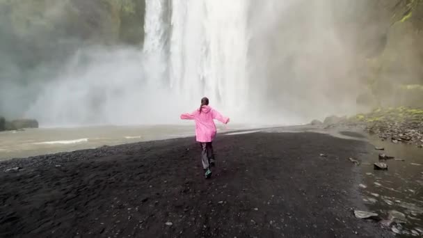 アイスランドの4K映像で冷たい滝に女の子が走る — ストック動画