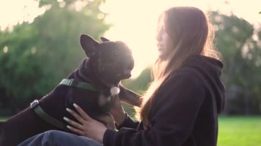 Genç bir kız köpeği ile parkta oynuyor. Çimlerin üzerinde 4K görüntüleri var.