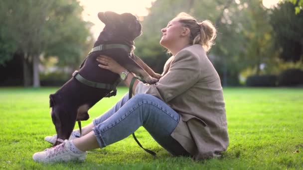 一位四十多岁的妇女在公园里的草地上和她的狗 一只法国斗牛犬玩耍 — 图库视频影像