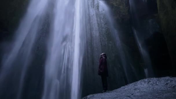 Ένα Κορίτσι Στέκεται Έναν Καταρράκτη Στην Ισλανδία Κατάσταση Διαλογισμού Πλάνα — Αρχείο Βίντεο