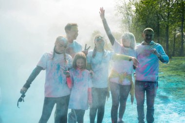 Holi 'yi pudra rengi ya da gulal ile kutlayan bir grup mutlu insan. Çimlerin üzerinde uzanmış, manzarası güzel. Hint festivali Holi kavramı.