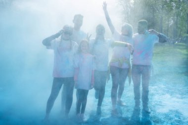 Holi 'yi pudra rengi ya da gulal ile kutlayan bir grup mutlu insan. Çimlerin üzerinde uzanmış, manzarası güzel. Hint festivali Holi kavramı.