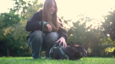 Genç bir kız köpeği ile parkta oynuyor. Çimlerin üzerinde 4K görüntüleri var.