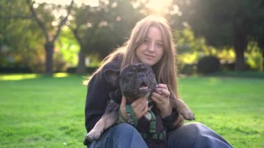 Genç bir kız köpeği ile parkta oynuyor. Çimlerin üzerinde 4K görüntüleri var.