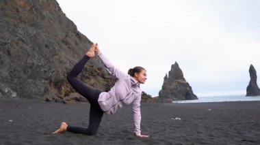İzlanda 'da Vik' in siyah plajında yoga yapan kız.