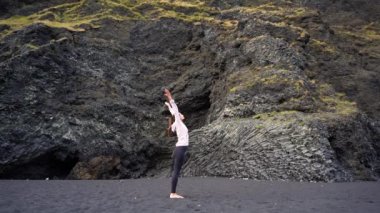 İzlanda 'da Vik' in siyah plajında yoga yapan kız.