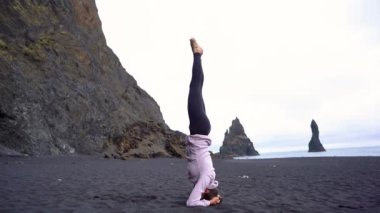 İzlanda 'da Vik' in siyah plajında yoga yapan kız.