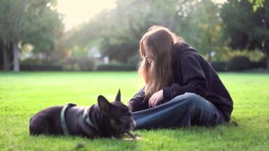 Genç bir kız köpeği ile parkta oynuyor. Çimlerin üzerinde 4K görüntüleri var.