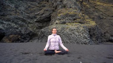 İzlanda 'da Vik' in siyah plajında yoga yapan kız.