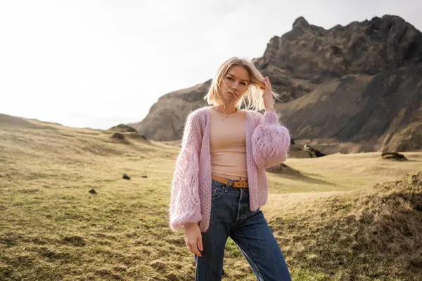 Fashion girl in a purple jacket poses against in mountains in Iceland
