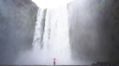 İzlanda 'da şelalenin başında duran bir kız meditasyonun 4K görüntülerinde.