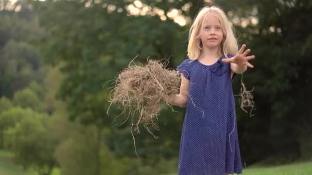 小さな金髪の少女はカメラで顔を作る — ストック動画