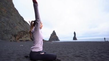 İzlanda 'da Vik' in siyah plajında yoga yapan kız.