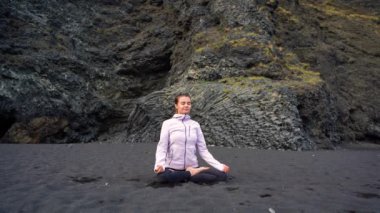İzlanda 'da Vik' in siyah plajında yoga yapan kız.