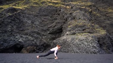 İzlanda 'da Vik' in siyah plajında yoga yapan kız.