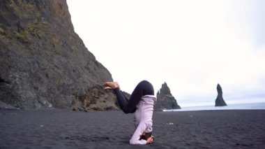 İzlanda 'da Vik' in siyah plajında yoga yapan kız.