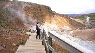 Kız turist İzlanda 'nın jeotermal gayzer bölgesinde yürüyor