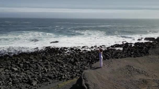 女孩在海边的岩石上做瑜伽 夕阳西下时从一架无人驾驶飞机上看到 — 图库视频影像