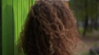 Kızıl saçlı kıvırcık kız dans ediyor parlak bir arka planda