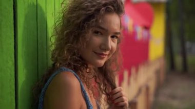 Kızıl saçlı kıvırcık kız dans ediyor parlak bir arka planda