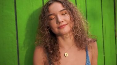 Kızıl saçlı kıvırcık kız dans ediyor parlak bir arka planda