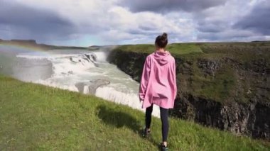 İzlanda 'da şelalenin başında duran bir kız meditasyonun 4K görüntülerinde.