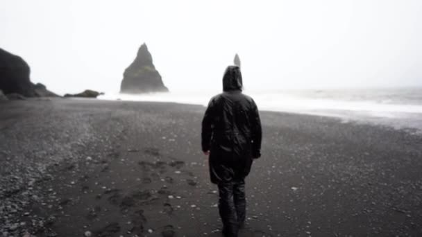 Cara Capa Preta Caminha Chuva Tempestade Longo Uma Praia Negra — Vídeo de Stock