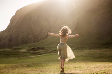 İzlanda 'da gün batımında hafif bir elbiseyle dans eden bir kız.