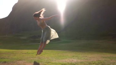 İzlanda 'da gün batımında hafif bir elbiseyle dans eden bir kız.