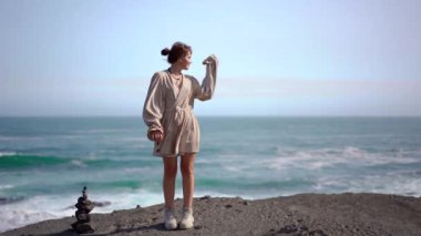 İzlanda 'da bej elbiseli bir kız okyanusta yürüyor.