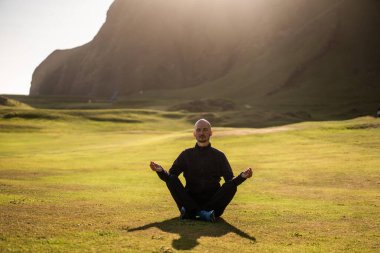 İzlanda 'da gün batımında doğada yoga yapan adam.