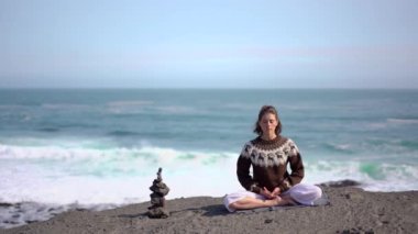 Kız okyanus ve İzlanda 'da dalgalar arasında meditasyon yapıyor.