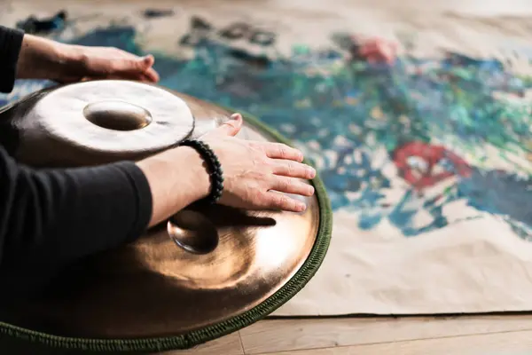 A musicians hand playing the handpan with other people. Handpan is a term for a group of musical instruments that are classified as a subset of the steelpan.